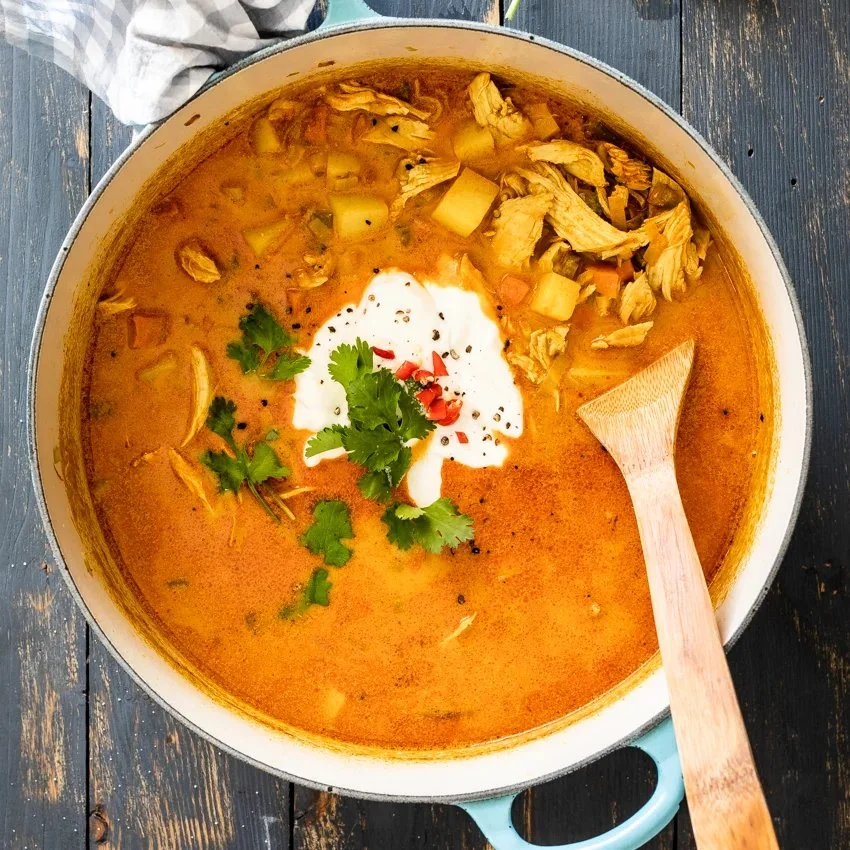 Creamy chicken curry soup garnished with fresh herbs in a bowl