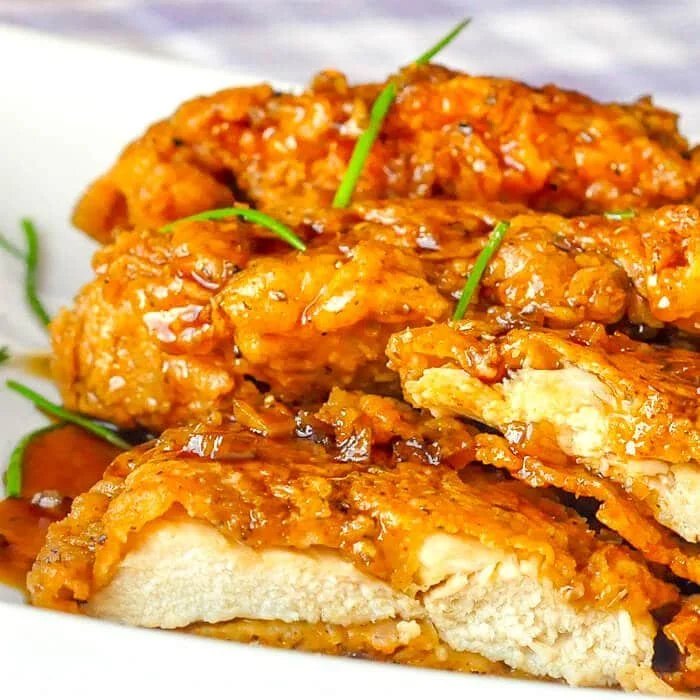 Plate of crispy Double Crunch Honey Garlic Chicken garnished with herbs