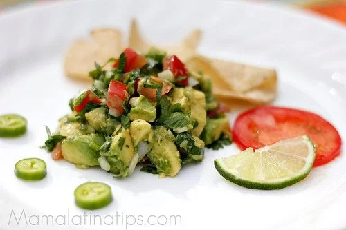 Bowl of fresh guacamole garnished with cilantro and lime slices.