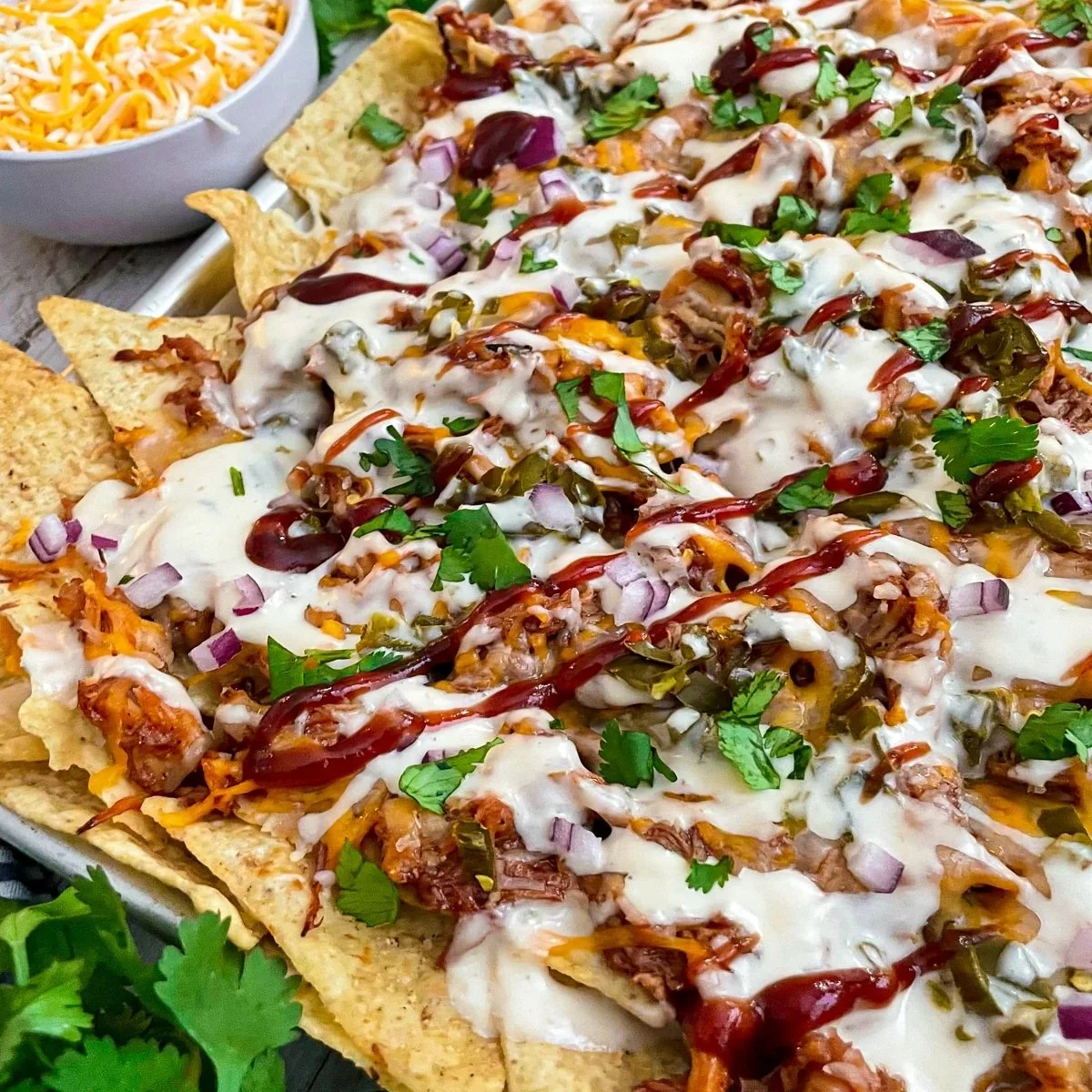 Sheet pan BBQ chicken nachos topped with cheese and jalapeños