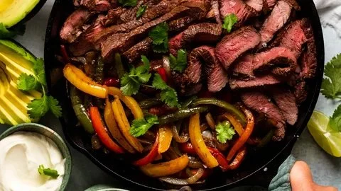 Sizzling beef steak fajitas served with colorful peppers and onions