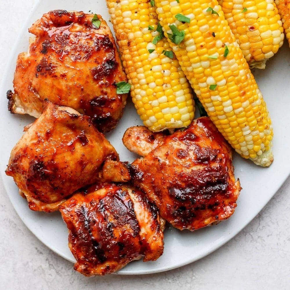 Smoky grilled BBQ chicken thighs on a serving platter