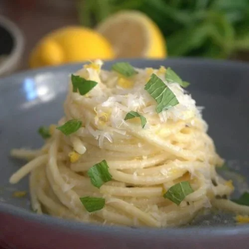 Plate of spaghetti with lemon zest and parsley, garnished for a fresh taste.