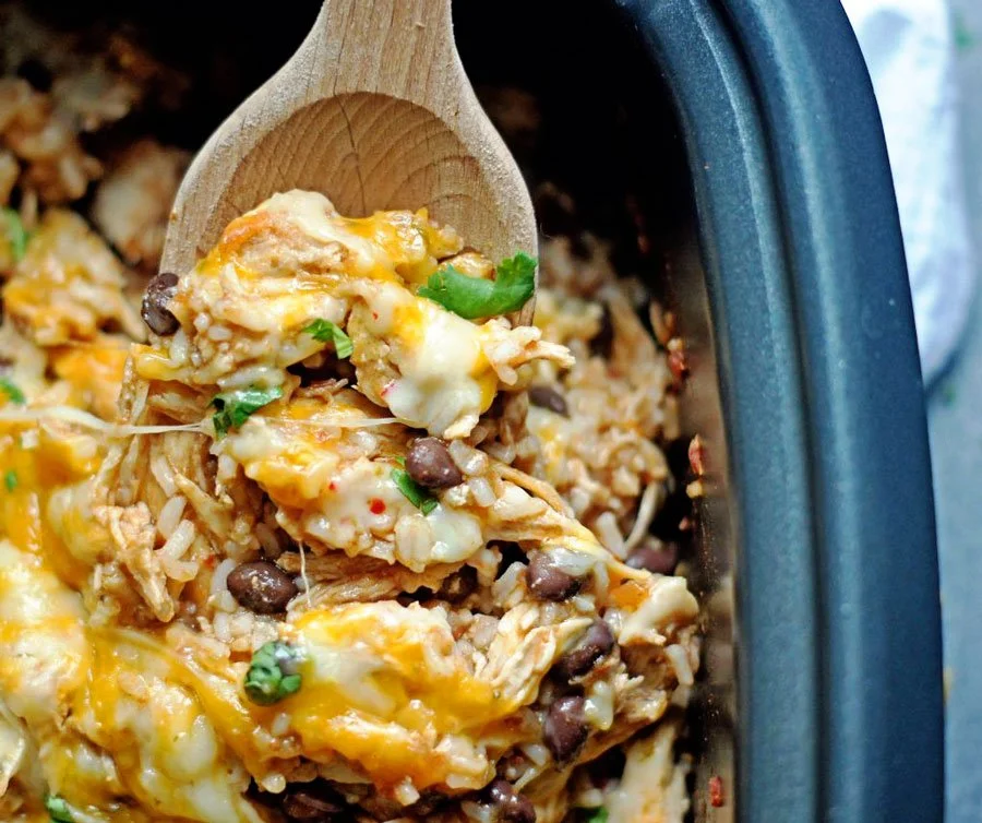 Spicy slow cooker chicken and rice served in a bowl garnished with herbs.