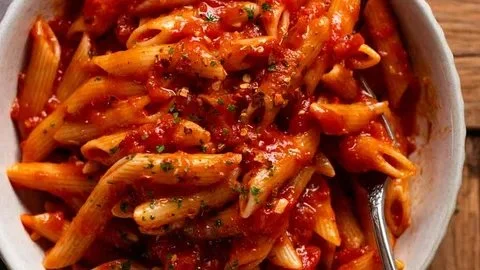 A delicious bowl of Spicy Tomato Penne Arrabbiata topped with fresh herbs.