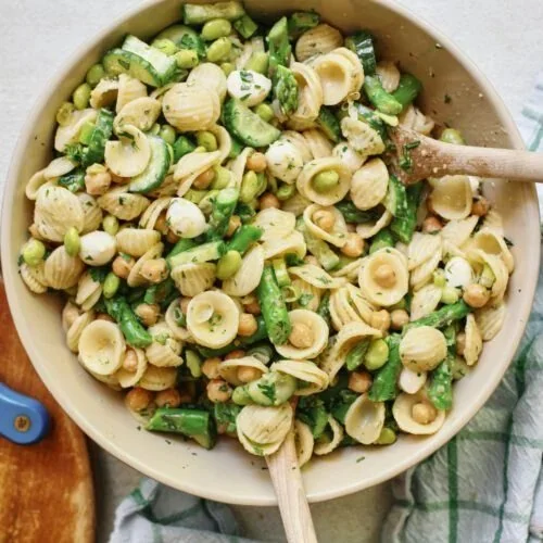 Bowl of vibrant Spring Lemon Herb Pasta garnished with fresh herbs and lemon.